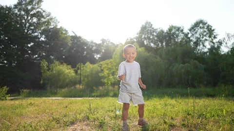 Young boy playing with red ball. Young boy walking outdoors with a child in Stock Footage 318011991