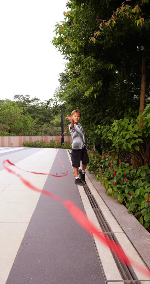 Young boy playing with red ribbon in a park, slow motion Stock Footage 304160215