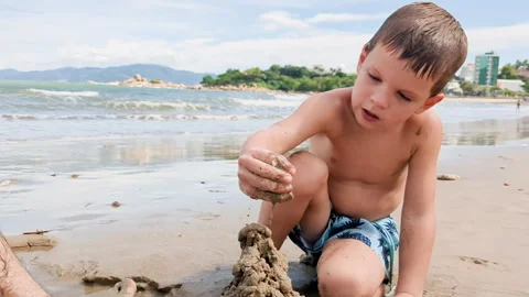 Young boy playing with sand at seaside. Caucasian kid take fun on coastline. Stock Footage 262414380