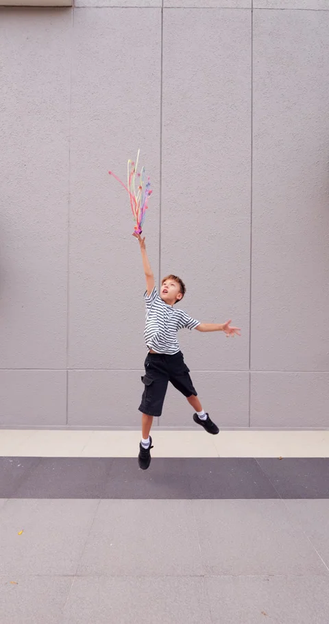 Young boy playing, send up colorful streamers confetti ribbons, slow motion Stock Footage 304160166
