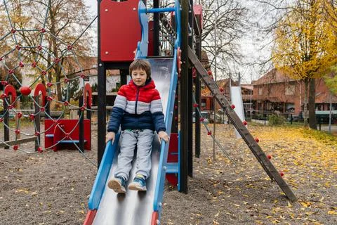 Young boy playing on slide at playground Stock Photos