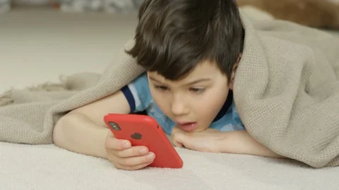 Young boy playing smartphone tablet at home 4K R3D Video stock 129050045