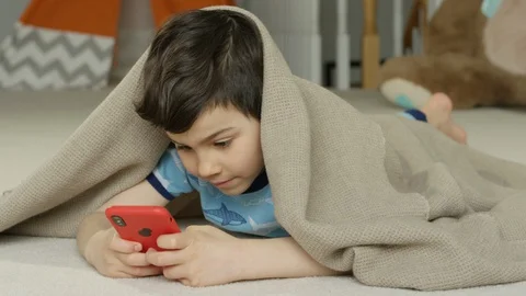 Young boy playing smartphone tablet at home 4K R3D Video stock 129050099