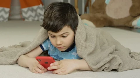 Young boy playing smartphone tablet at home 4K R3D Video stock 129050603