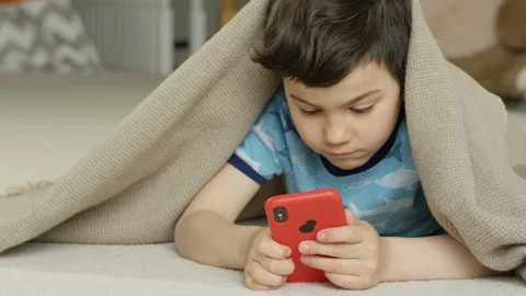 Young boy playing smartphone tablet at home 4K R3D Video stock 129051350