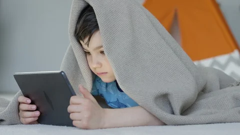 Young boy playing smartphone tablet at home 4K R3D Video stock 129052431