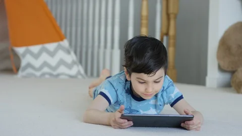 Young boy playing smartphone tablet at home 4K R3D Video stock 129053157
