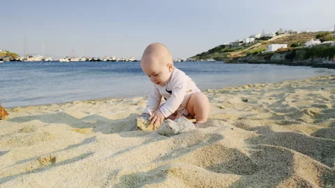 Young boy playing in soft sand on a sunny beach, joyfully exploring the Stock Footage 317329571