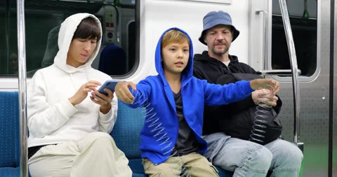 Young boy playing with spring toy on subway train with family Stock Footage 303986376