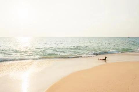 Young boy playing in the surf on sunset beach. Stock Photos