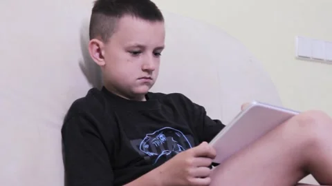 Young boy playing in a tablet on a white sofa Stock Footage 199206939