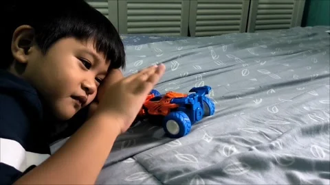 Young Boy Playing with a Toy Car on a Bed Stock Footage 312104530