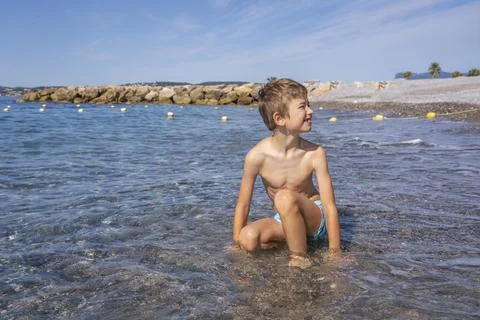 Young boy playing with waves on the beach by the sea. Holidays with children  Stock Photos