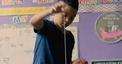 Young boy playing with a yo-yo in a classroom Stock Footage 108787009