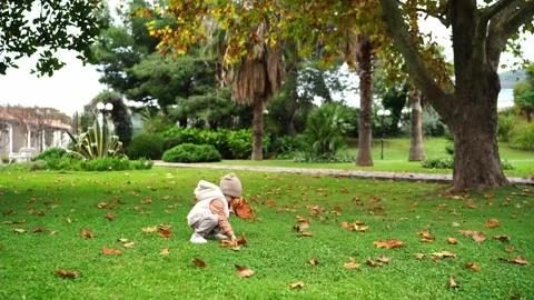 A young boy plays amidst the trees and grass in a sunny park Stock Footage 285793546