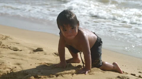 A young boy plays with a beach ball in the sand and runs into the ocean Stock Footage 33894151