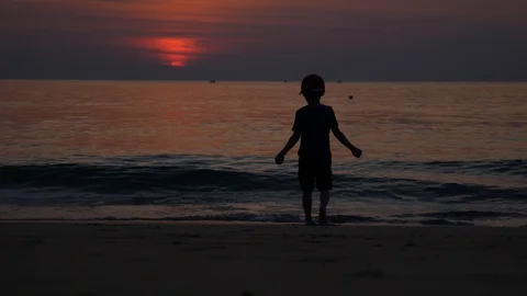 A young boy plays on the beach at sunset. 4k Stock Footage 108312911