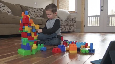 Young boy plays with building blocks with tablet Stock Footage 85365456