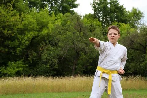 Young boy practices karate in a green field on a sunny day Stock Photos