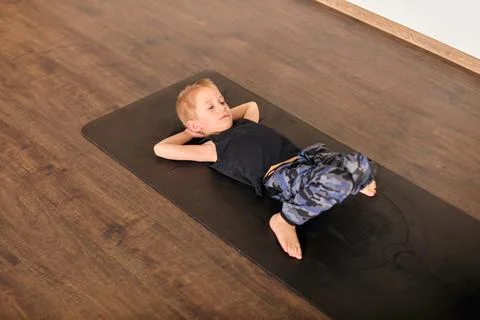 Young boy practicing floor yoga in calm indoor setting Stock Photos
