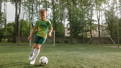 A young boy is practicing his soccer skills on an outdoor football field Stock Footage 284158806