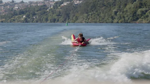 Young boy practicing wakesurfing on a river Stock Footage 300579704