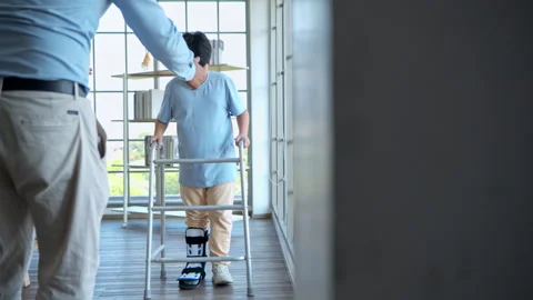 Young boy practicing walking with mobility aid under parental supervision Stock Footage 339061223