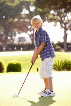 Young Boy Practising Golf On Putting On Green Photos