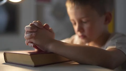 Young boy is praying. A boy prays for a child religion. Religious book of prayer Stock Footage 316609701
