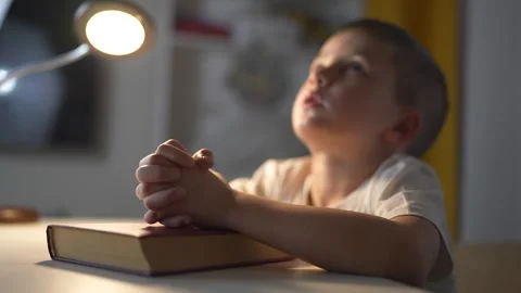 Young boy is praying. A boy prays for a child religion. Religious book of prayer Stock Footage 317691154