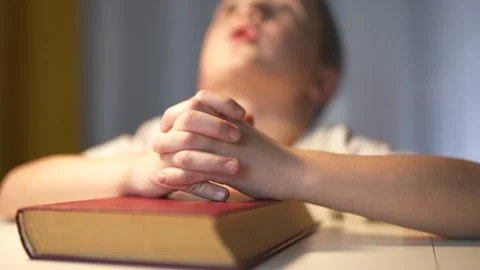 Young boy is praying. A boy prays for a child religion. Religious book lifestyle Stock Footage 317691343