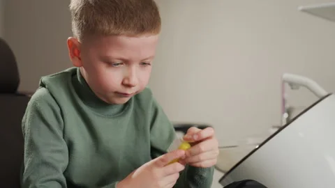 Young boy preparing for dentist appointment by opening new floss in clinical Stock Footage 345078768