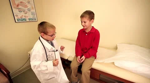 Young boy pretending to be doctor doing a reflex exam on another child Stock Footage