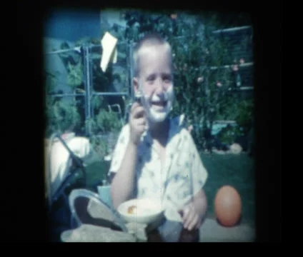 Young boy pretends to shave with dads old fashioned razor Stock Footage 33843934