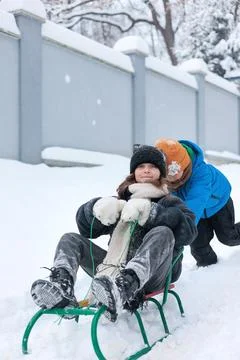 Young boy pulling girl on sled in winter park Stock Photos