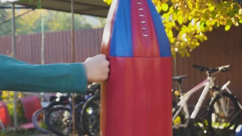 Young boy punching a big red bag. Sport activity outdoor at sunset. Close Up  Video stock 98377326