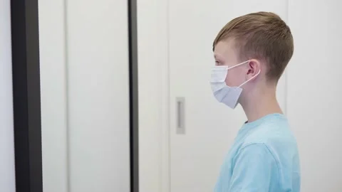 A young boy puts on a face mask, looks in mirror then takes it off in an Stock Footage 138163772