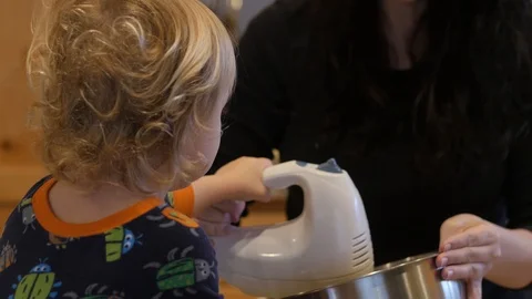 Young boy puts his hand on his mothers as they use the electric mixer  Stockbeeldmateriaal 86814018