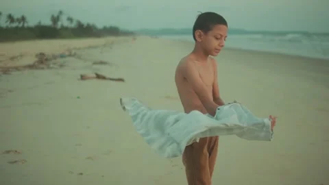 Young boy putting on a shirt after swimming at the beach. Candid summer Stock Footage 340219063