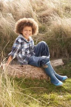 Young boy putting on wellington boots Stock Photos