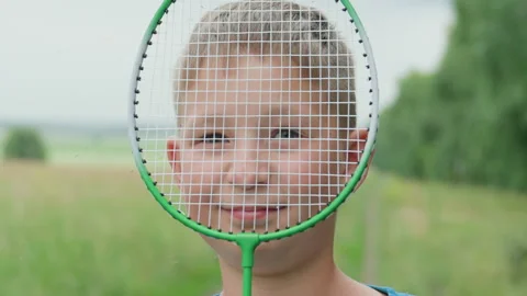 Young boy with racket smiling, Boy in green field with racket smiling, Adorable Stock Footage 324870529