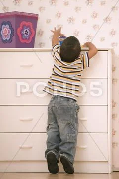 Young boy reaching on dresser Stock Photos
