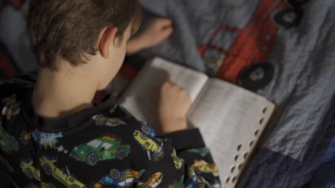 Young boy reading Bible by bed in worship and praise to Jesus. Stock Footage 123910933