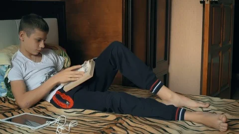 Young boy reading book on sofa. Child reading book. Kid doing homework Stock Footage 69865467