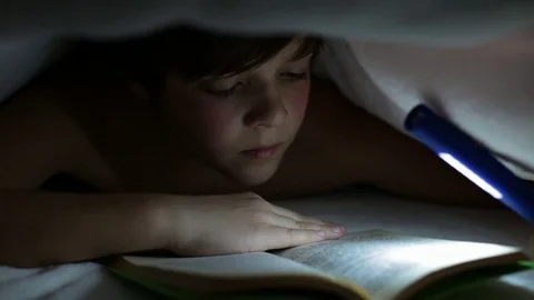 Young boy reading a captivating book at night Video stock 80241910