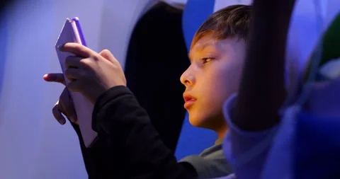 Young boy reading e-book during night flight, warm glow on his face Video stock 303991802