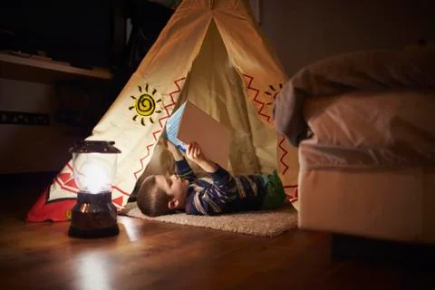 Young Boy Reading Inside Tent Set Up Indoors Stock Photos