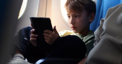 Young boy reading tablet on airplane during flight Stock Footage 303994403