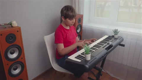 Young Boy In Red Shirt Playing Electronic Keyboard Synthesizer At Home 库存影片 342034531