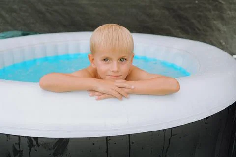 Young Boy Relaxing in Inflatable Pool with Calm Expression Foto stock